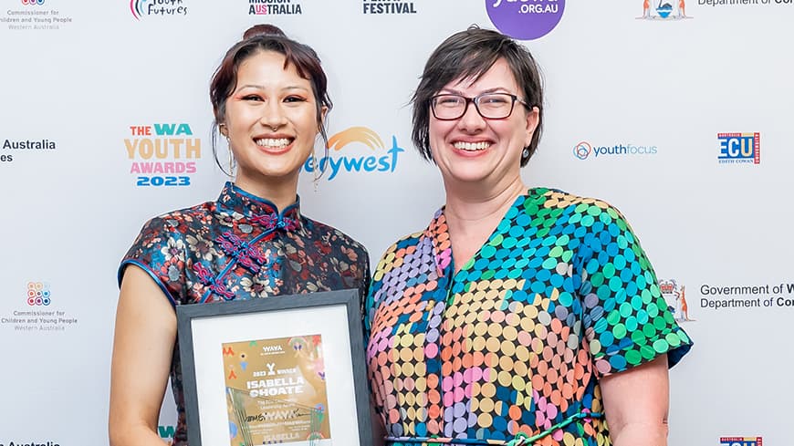 Isabella Choate and ECU's Dr Fiona Navin are dressed in colourful clothing, they both grin and hold the ECU Community Leadership Award.