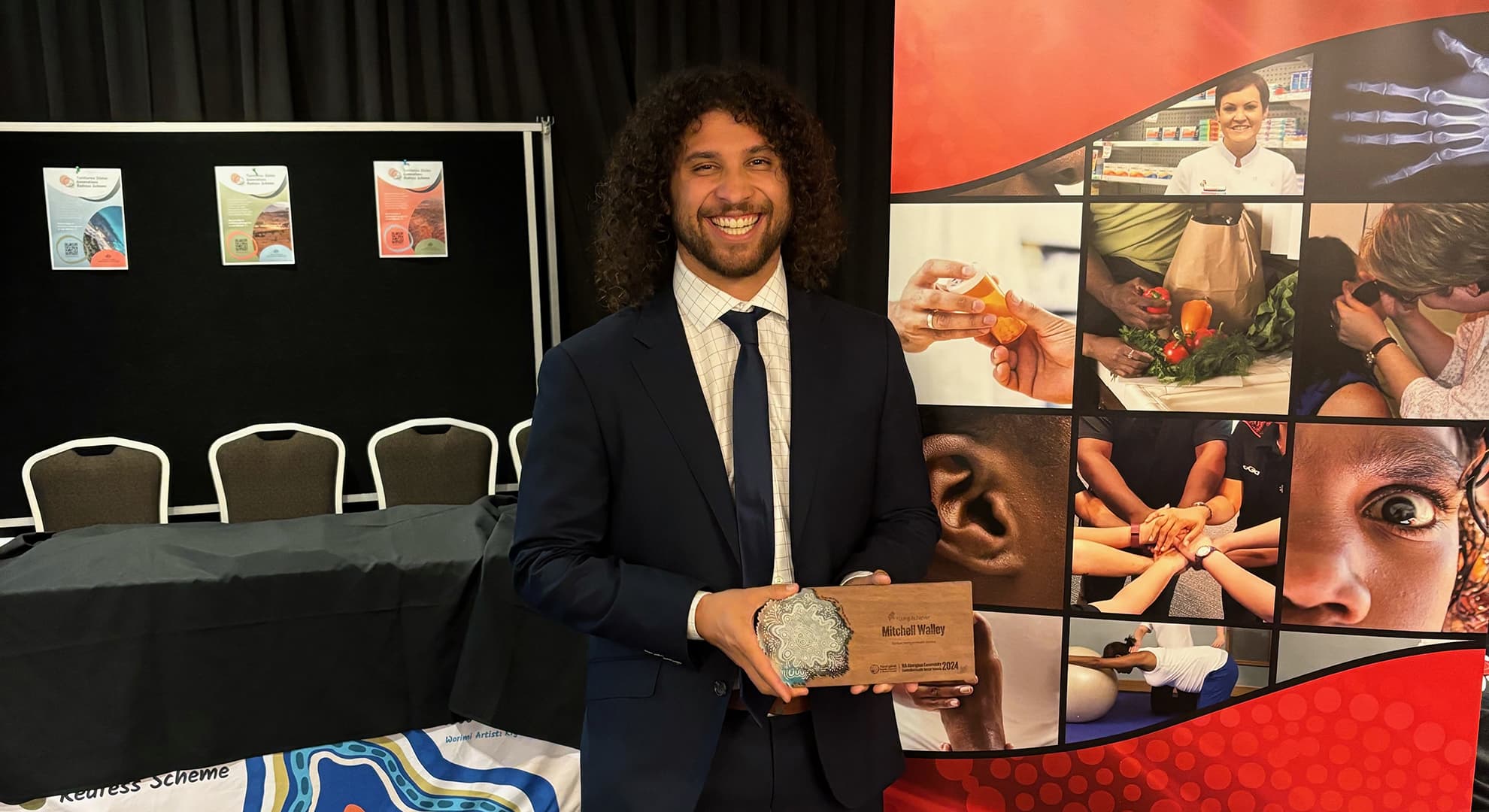 Mitch Walley wears a suit holding his award.