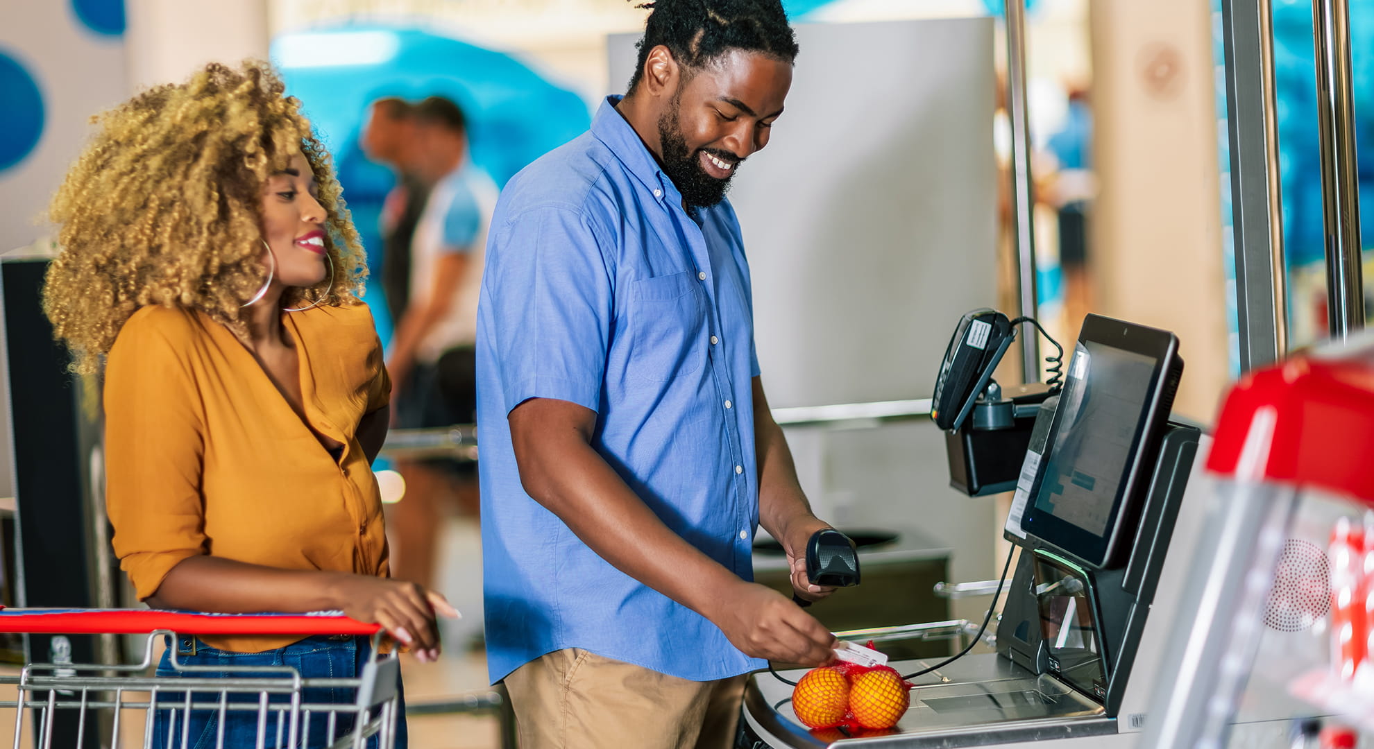 Man and woman standing at self-checkout.