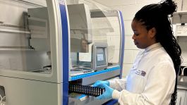 Female lab staff in white lab coat using the machine