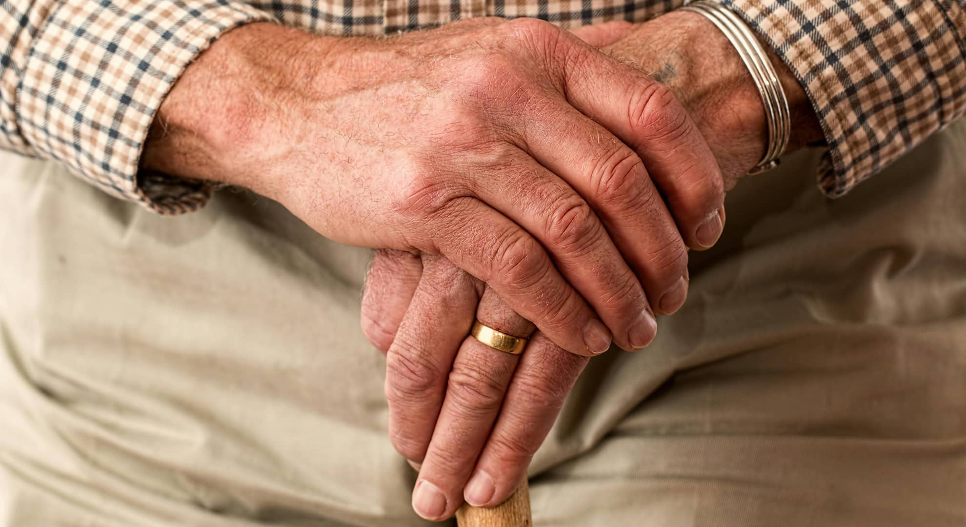 Old man's hands holding cane