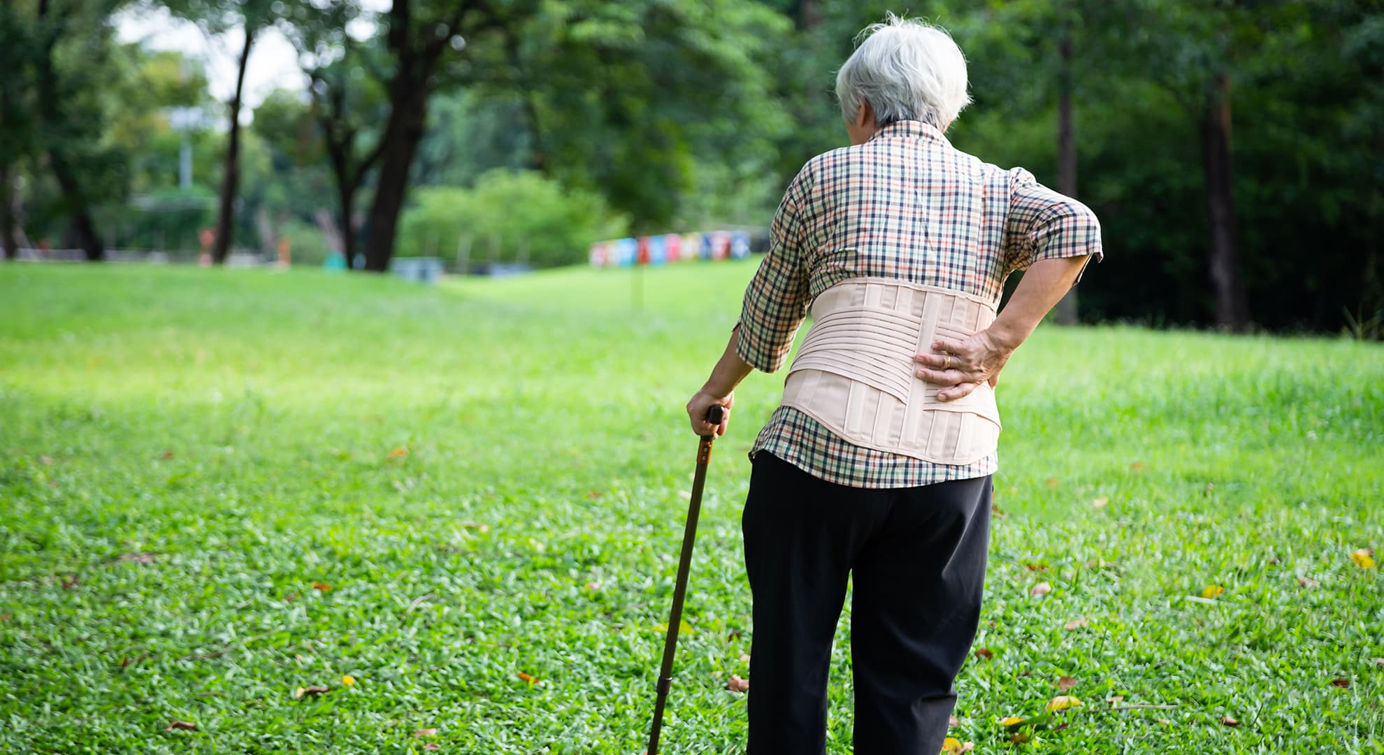 Old lady walking in park with a cane.