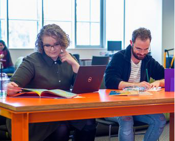 Two students sit at a shared desk, deeply engaged in their studies while preparing for exams.