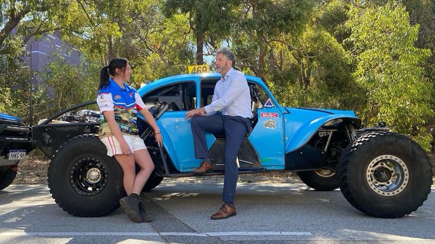 Lecture sitting on race car talking to student