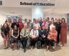 The first early childhood education cohort who began their studies in 1974 alongside Alumni, staff and friends gather for a group photo in front of a School of Education sign at the ECU Mount Lawley Campus.