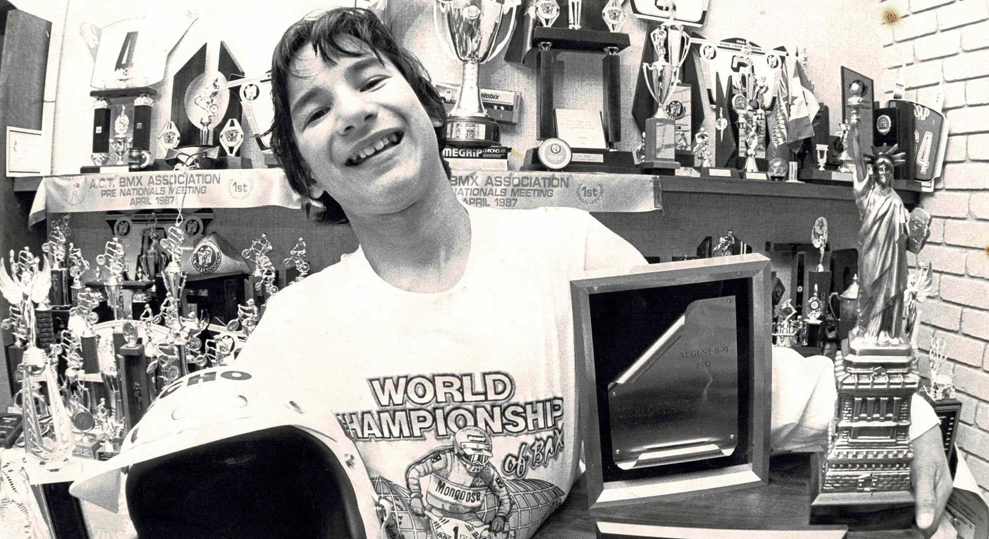 A black and white photograph of Daniel Sprague grinning holding his BMX award.