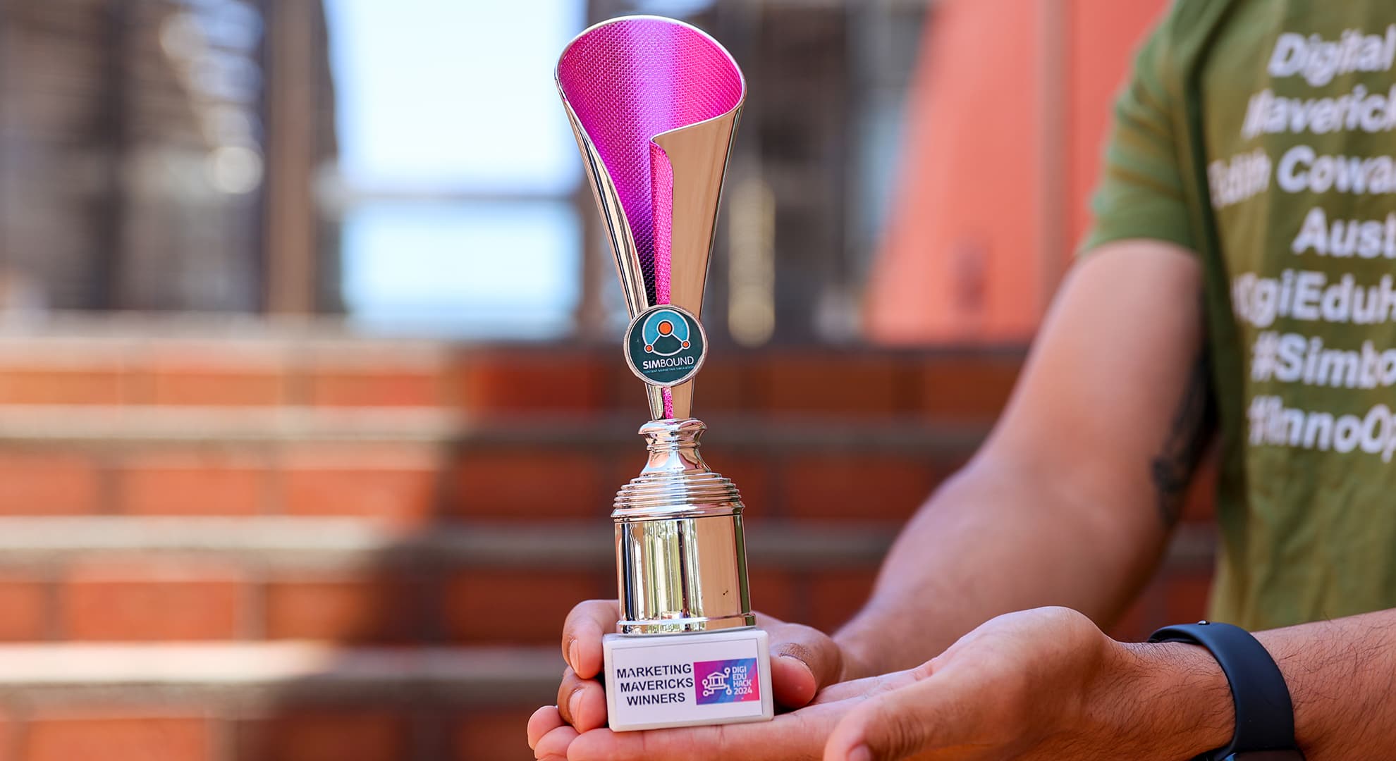 Hands holding the Marketing Mavericks trophy.