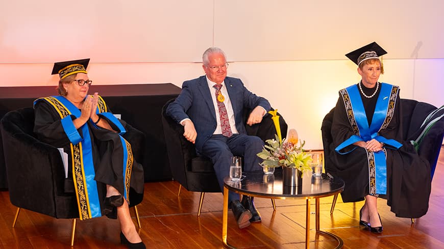 three people sitting in armchairs on stage