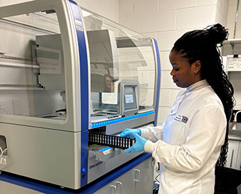 Woman in lab coat using the QIAsymphony instrument