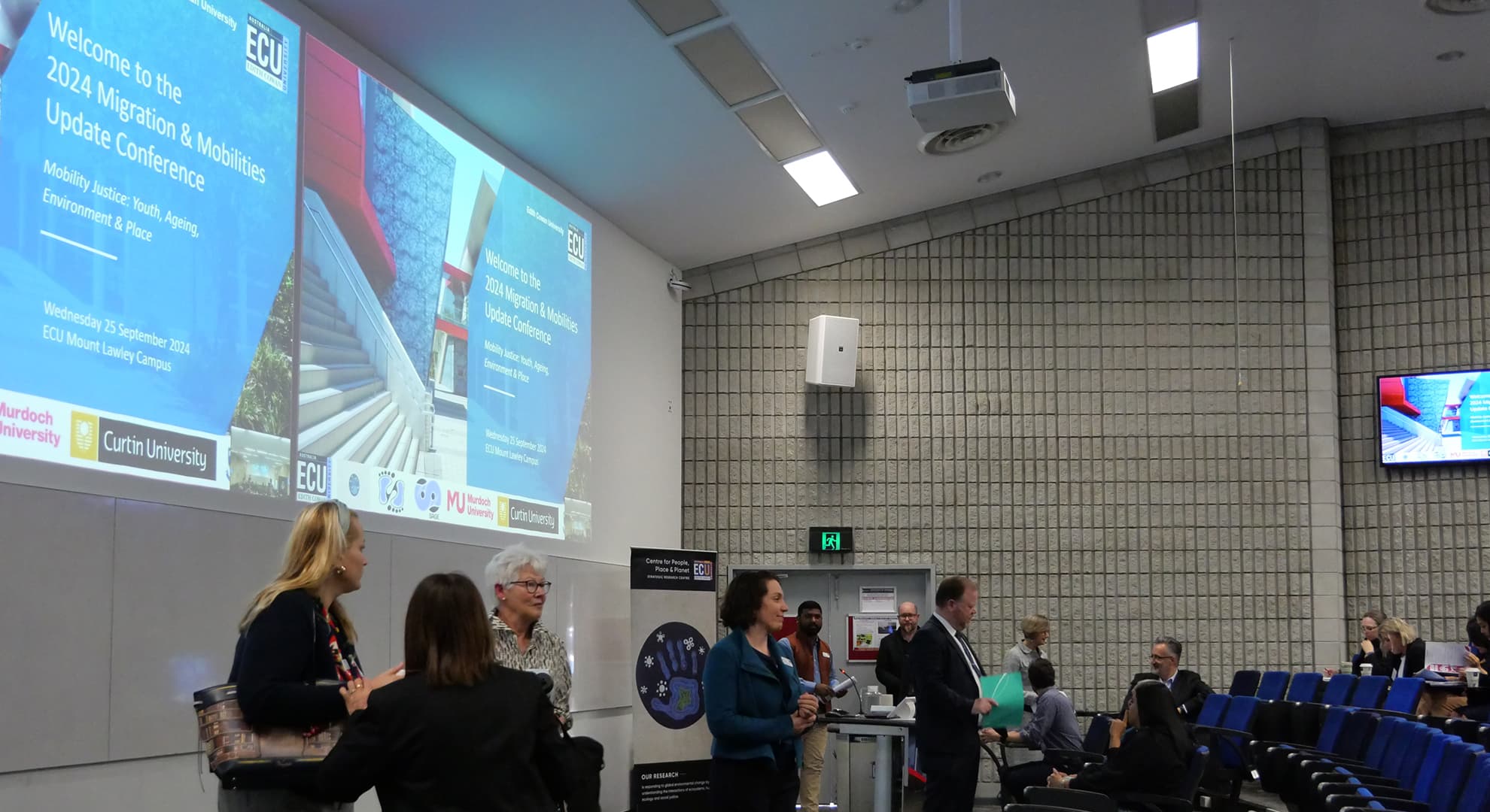 A group of academics, government representatives, students and community gathered in a lecture hall.