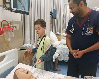 Children's University member learning how ECU nurses train at the South West Campus Demonstration Ward. The student is interacting with the medical equipment alongside an ECU lecturer.