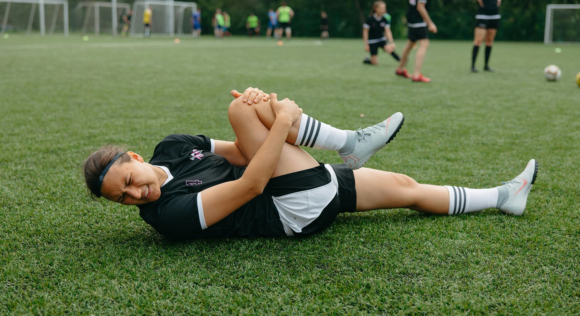 Female soccer player laying on the ground holding her knee