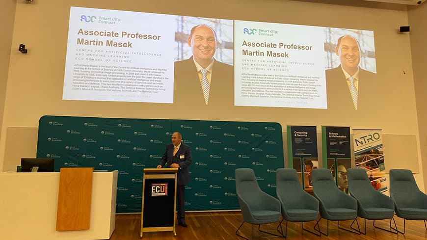 Associate Professor Martin Masek standing at the lectern giving the sponsor address at a forum.