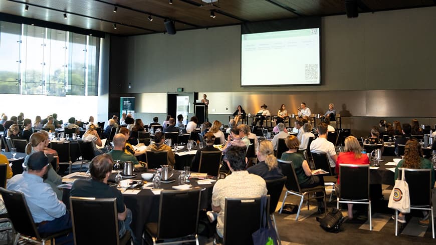 A function room filled with people and a stage and presentation for an urban biodiversity workshop.