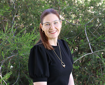 A portrait photo of Mrs Leonie Menzel smiling standing in front of a tree