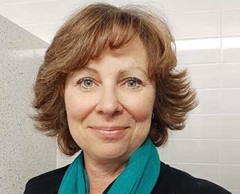 Jacquie Irving wearing a green scarf facing forward and smiling