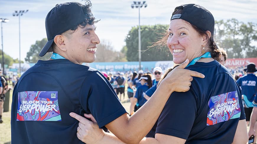 Two HBF Run for a Reason participants point to their t-shirts that say unlock your superpower.