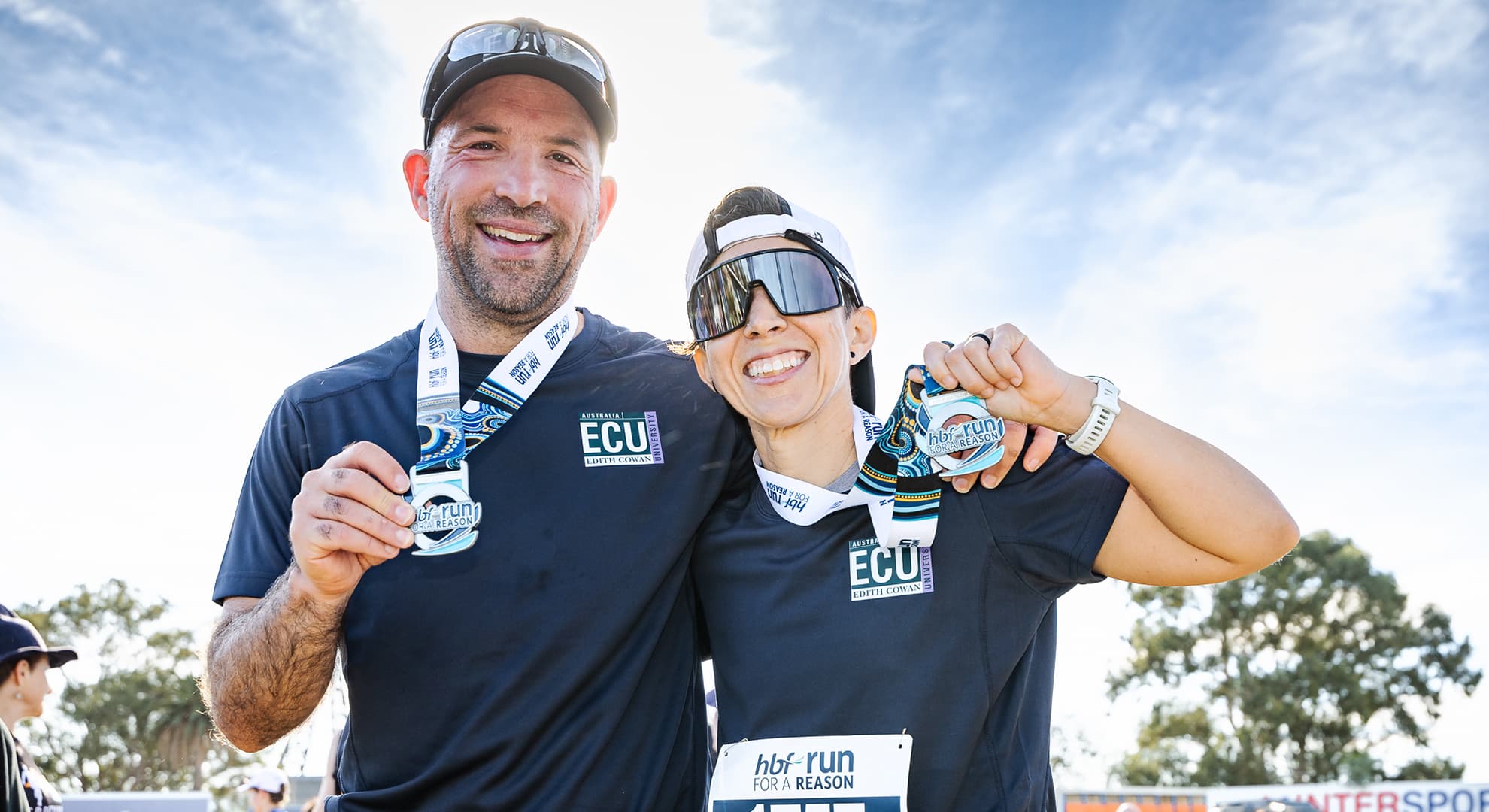 Two half marathon runners grin and hold up their medals at the HBF Run for a Reason.