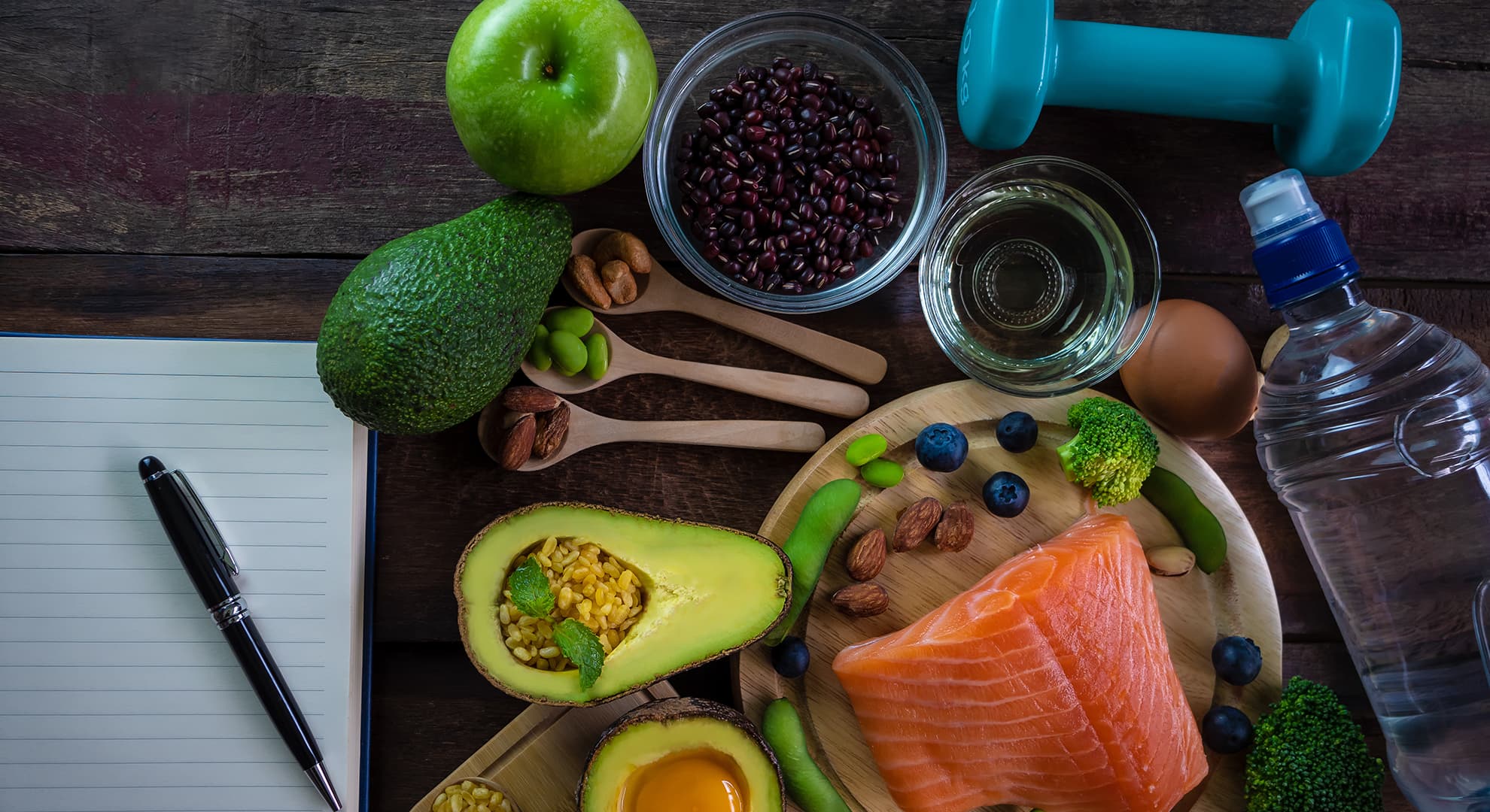 Various raw foods, a water bottle, a weight and a notebook and pen.