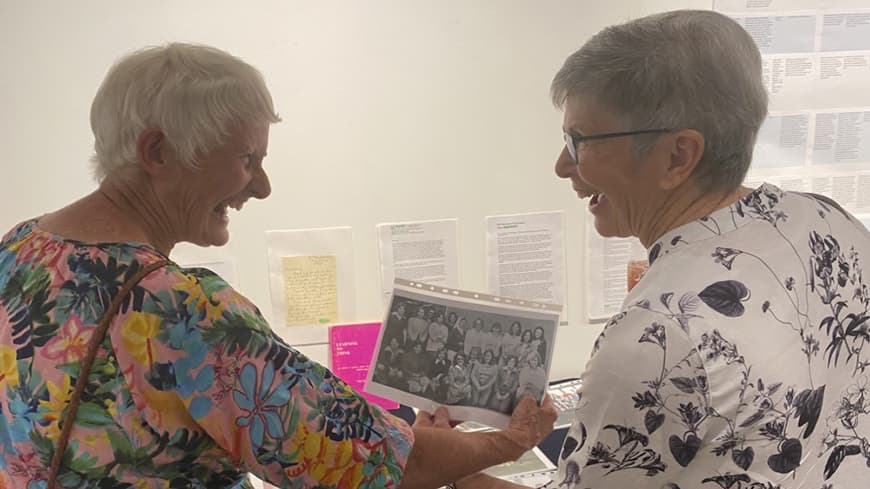 Two ECU alumni look at an old black and white photograph.