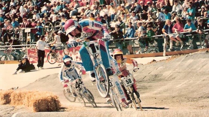 Daniel Sprague in pink, blue and white BMX gear in the middle of a race.