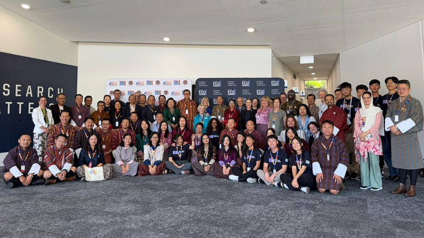 Large group photograph of Bhutanese dressed and Australian delegates in grey carpeted space