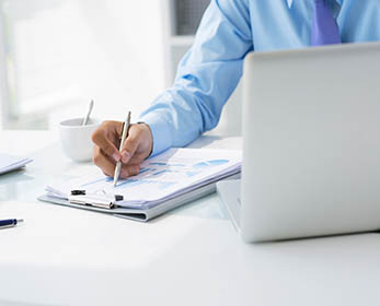 man's hand holding a pen and computer