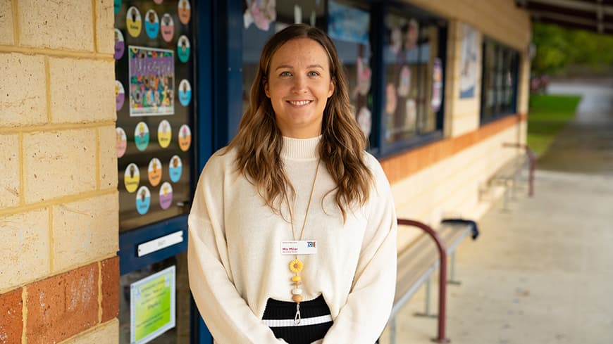 Teaching student Mindsey Miller outside the classroom wearing a white sweater.