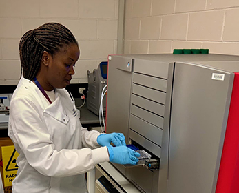 Female in white lab coat using the gene titan machine