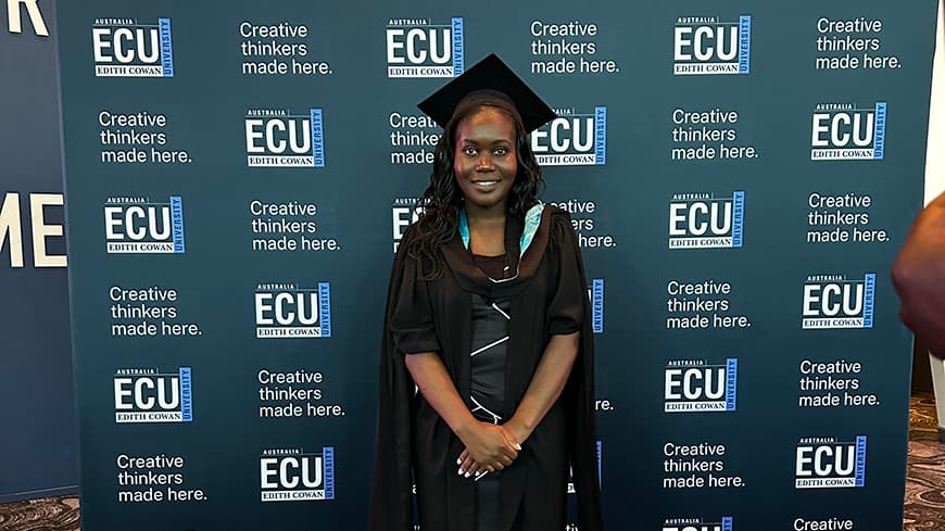 Purity Osiako wears a black dress, a graduation gown, regalia, and a cap.