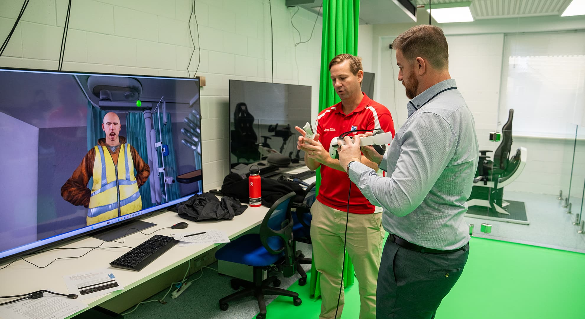 Two men standing in front of a VR screen.