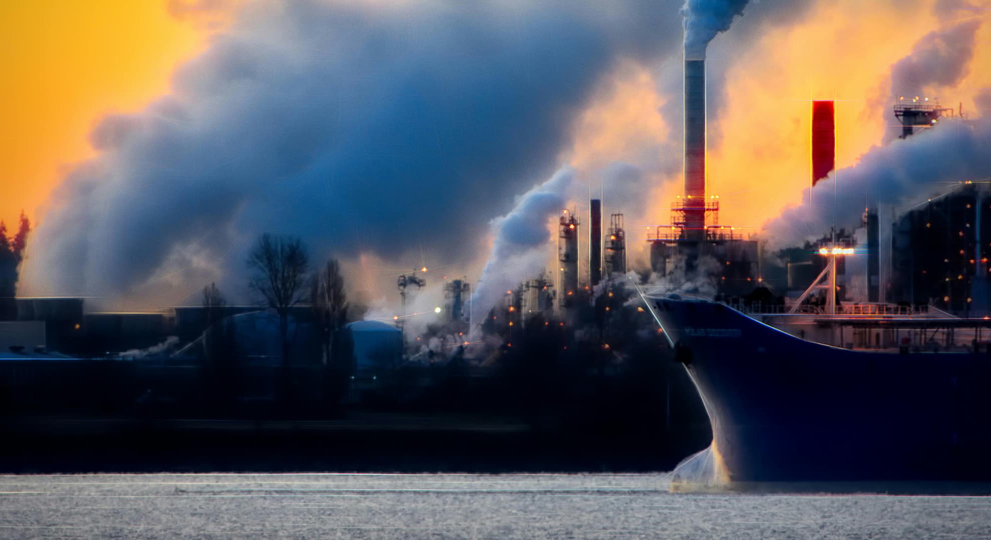 A container ship sailing on front of smoke stacks