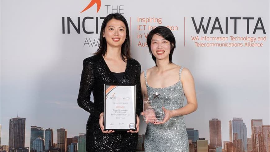 Young woman in black gown next to young woman in silver gown in front of branded banner for INCITE Awards, holding their award certificate