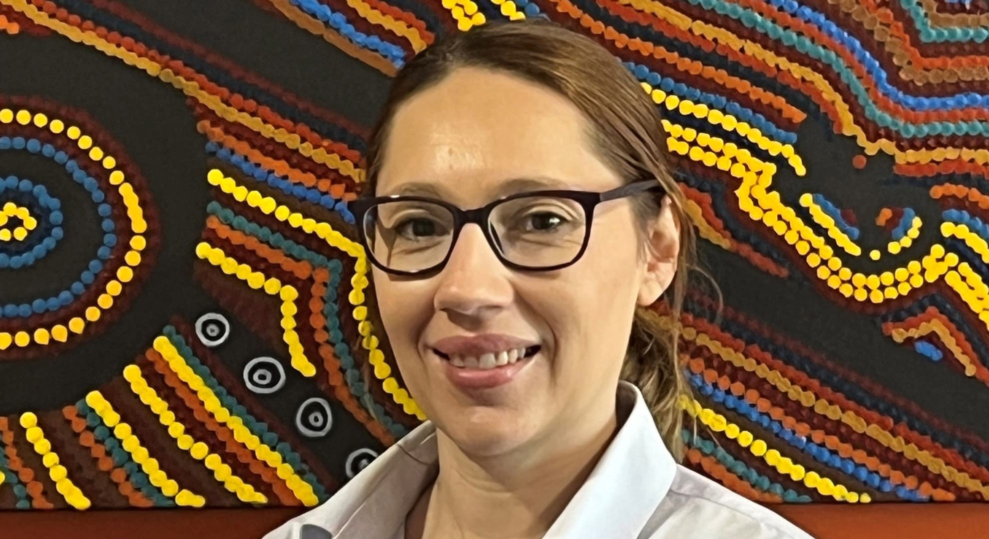 Woman standing before Aboriginal dot painting artwork