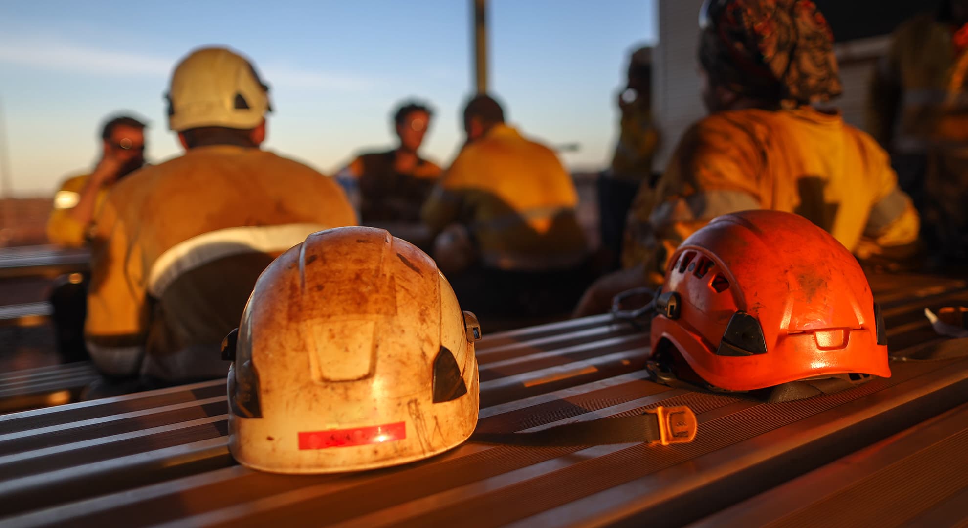 Mining safety helmets with miners in the background.