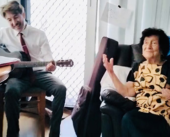 Male guitarist singing with an elderly female