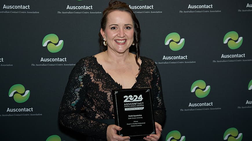 Heidi Apostoles in a black evening dress, holding her award at the 2024 Auscontact Awards with the Aus contact banner in the background