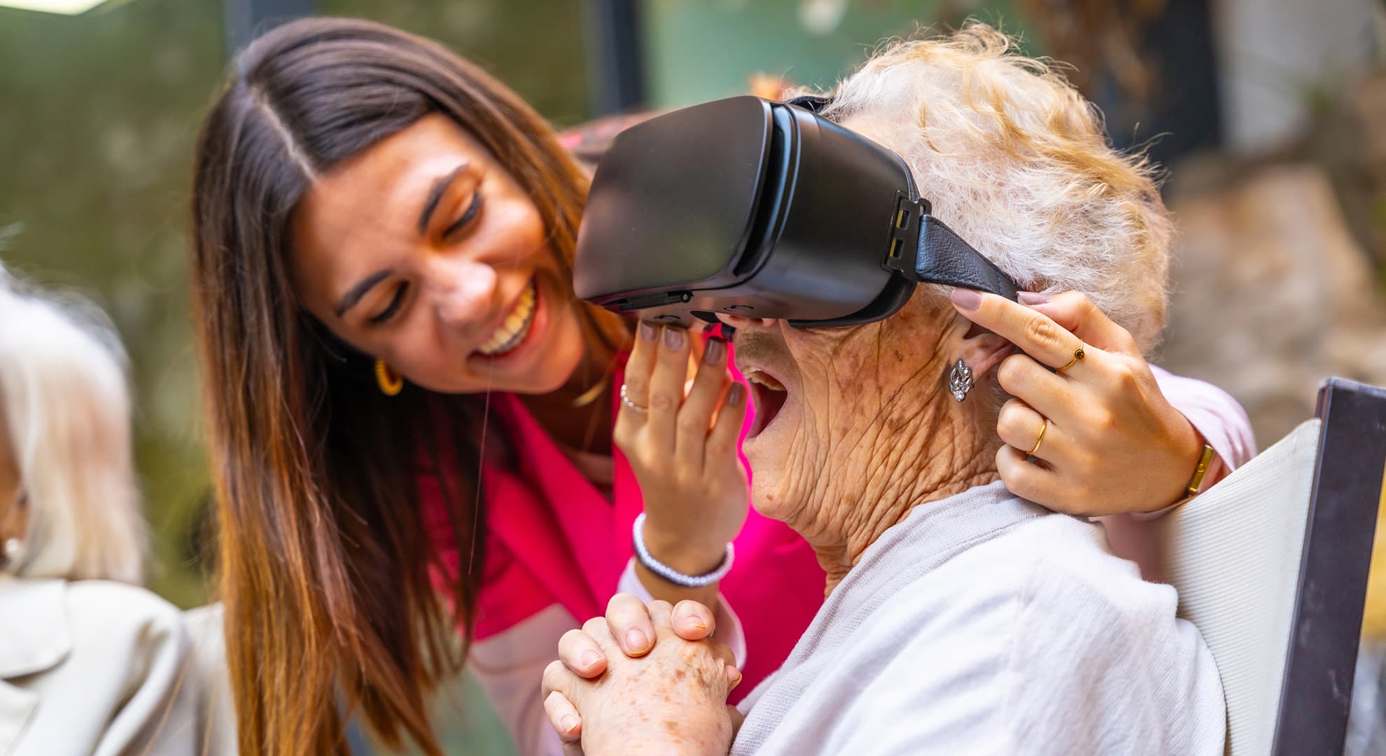 Smiling nurse holding VR headset on older woman's head