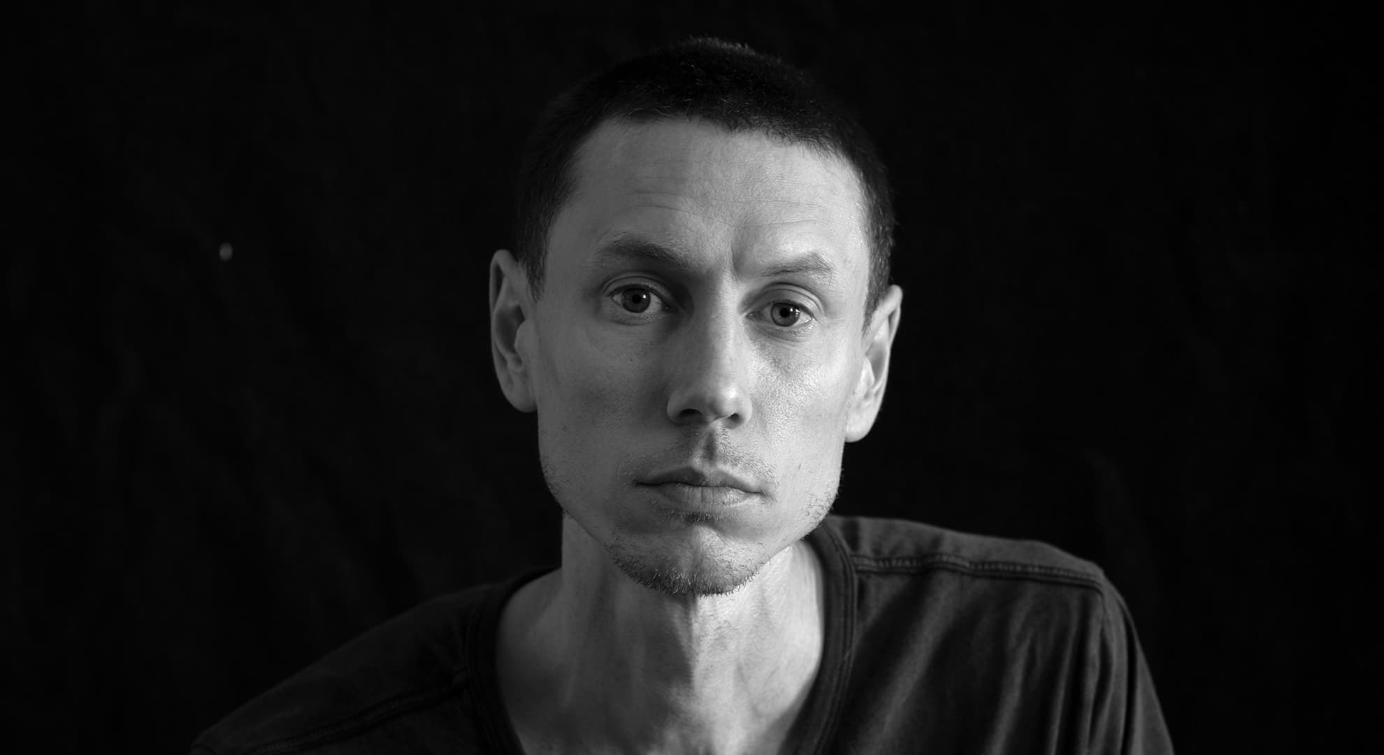 A black and white portrait of Jacobus Capone who has short hair, wears a slouchy t-shirt and looks calm.