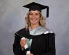 Portrait photo of Graduate speaker Alexis Martin in her graduation regalia, hat and holding her testamur.