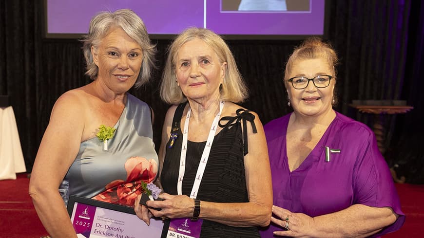 Three people standing facing camera with award certificate