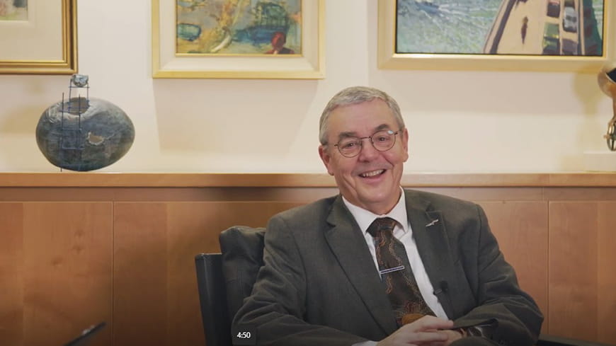 businessman in suit sitting in front of cabinet and artwork smiling