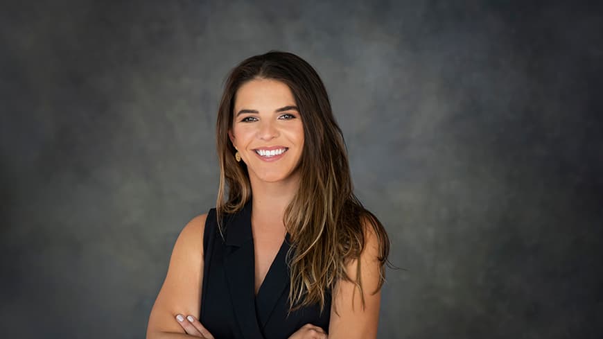 Smiling person in front of dark grey background.