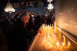 Photograph of an elderly female light a candle at a vigil