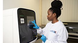 Photo of a female research assistant in white lab coat using the QuantStudio