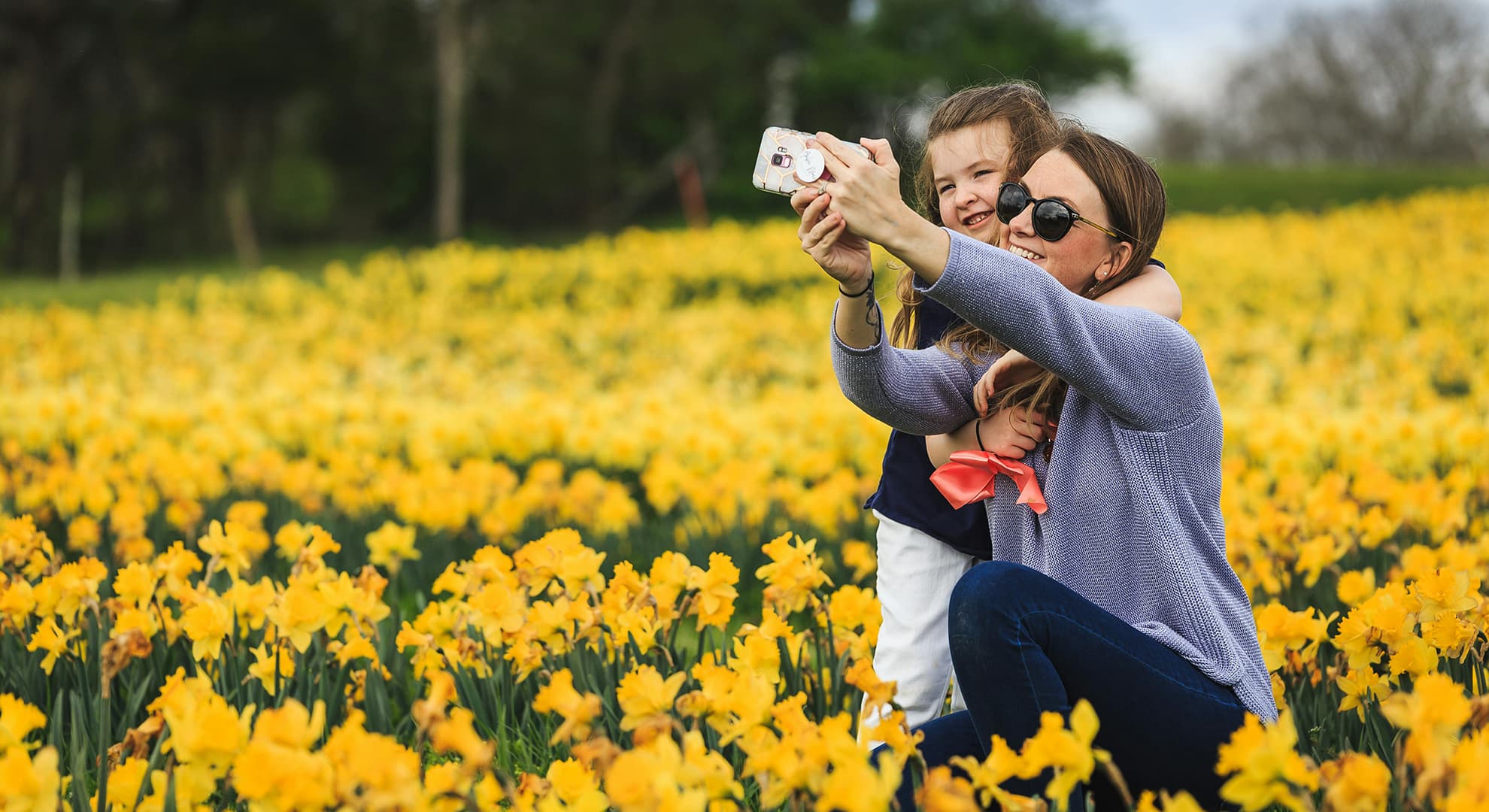 Mum and daughter taking a selfie in a field of flowers.